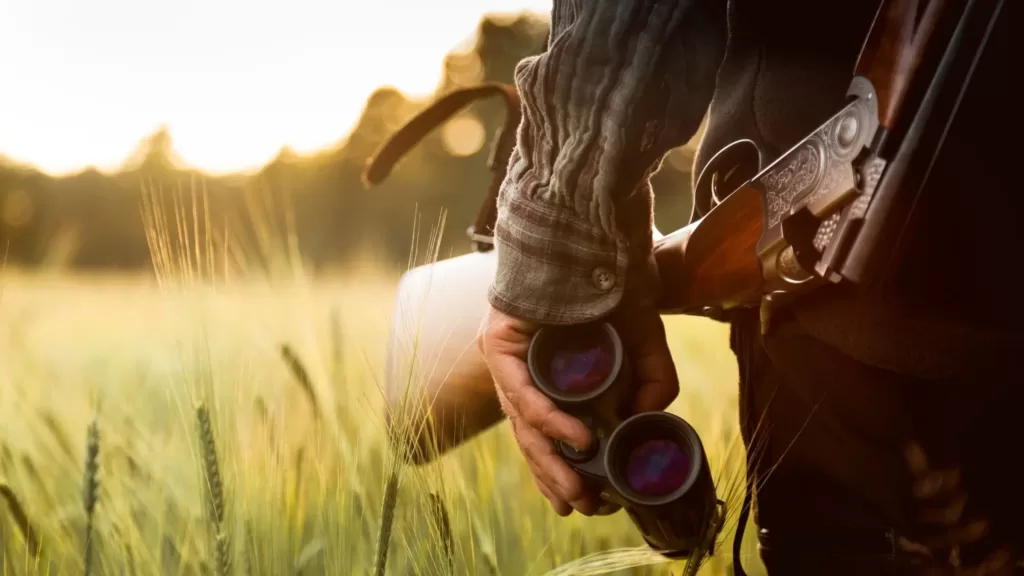 hunter holding compact binoculars